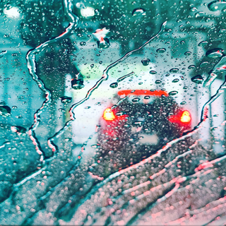 car lights through a car wash water-covered windshield