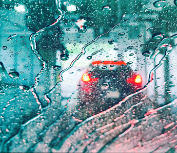 car lights through a car wash water-covered windshield