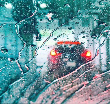 car lights through a car wash water-covered windshield