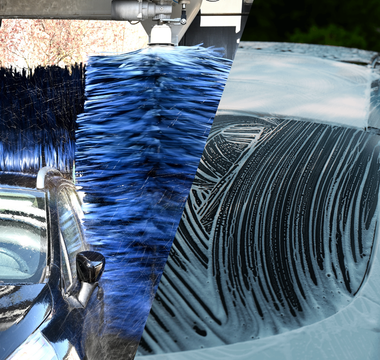 Car being washed with a foam lance vs an automatic car wash tunnel